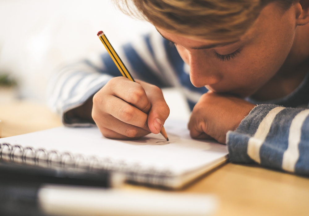 Schüler zeichnet mit Bleistift auf dem Notebook und macht Hausaufgaben