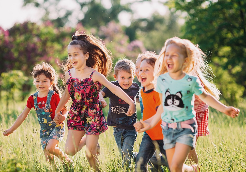 Gruppe von Kindern läuft im Park an einem sonnigen Sommertag