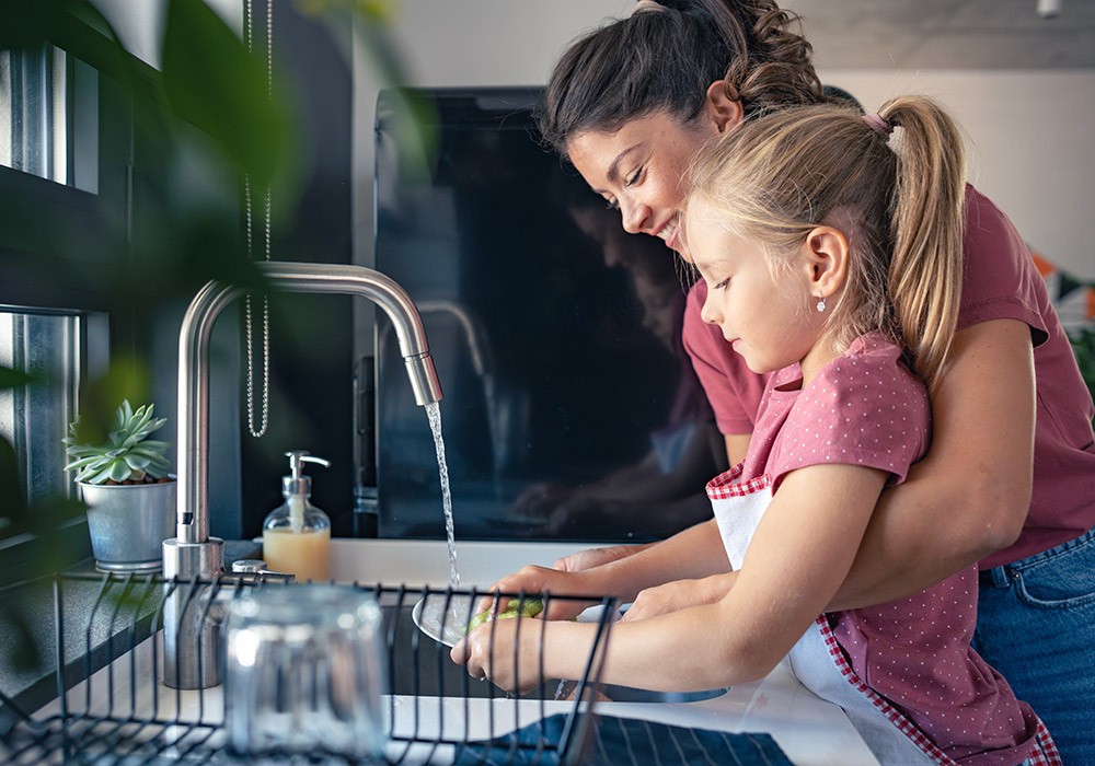 Ein kleines Mädchen hilft ihrer Mutter beim Abwasch